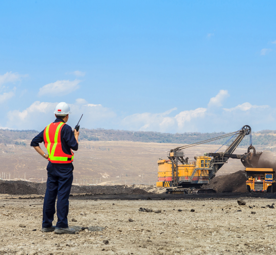 Ingeniero supervisando una cantera con maquinaria en funcionamiento, simbolizando experiencia y compromiso en minería responsable